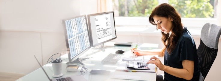 An accountant sitting at a desk with a computer doing taxes
